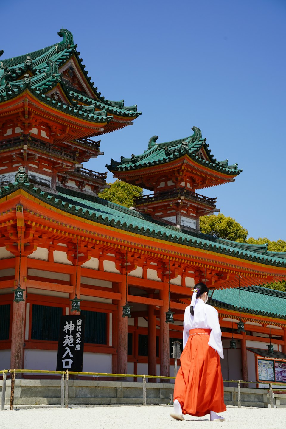 伝統的な東アジアの衣装を着た人が、装飾的な寺院に向かって歩いています。